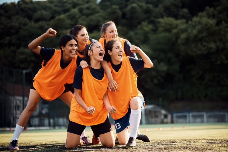 a group of female soccer players pose for a celebratory picture on the field